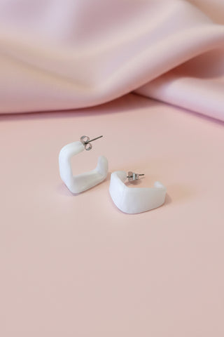 White hoop earrings on a textured white surface