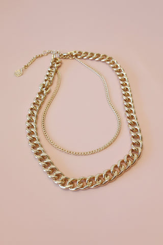 gold chain necklace on a blush tone surface