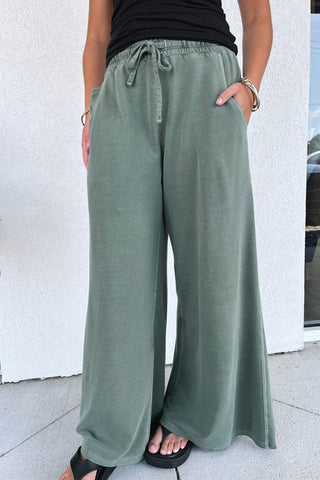 wide-leg, army green, terry sweatpants on a model in front of a building
