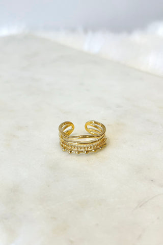 Gold adjustable ring on a smooth blush surface.