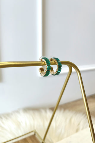 Green hoop earrings on a gold stand with a white background