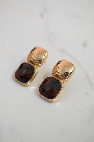 Gold and brown earrings on a light gray background