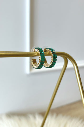 Green hoop earrings on a gold stand with a blurred background