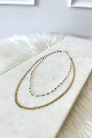 Gold necklace with small pearls on a marble surface