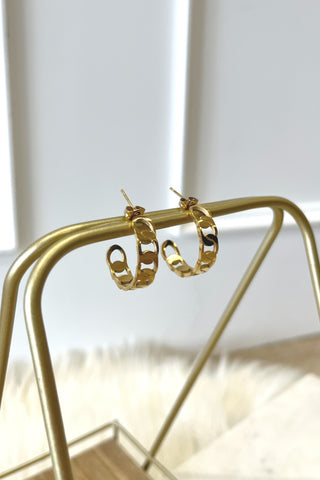 Gold hoop earrings on a gold stand with a blurred background