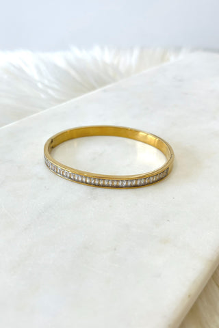 Gold bracelet with crystals on a marble surface