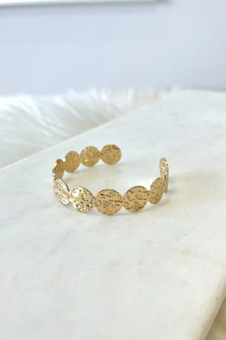 Gold bracelet on a white marble surface
