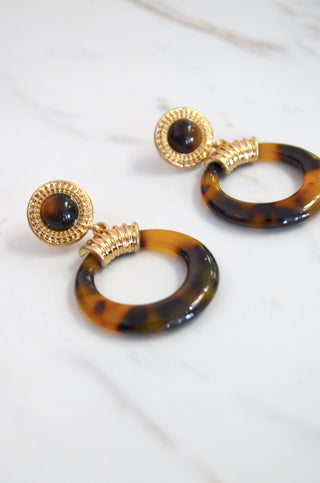 Tortoiseshell hoop earrings with gold accents on a white background