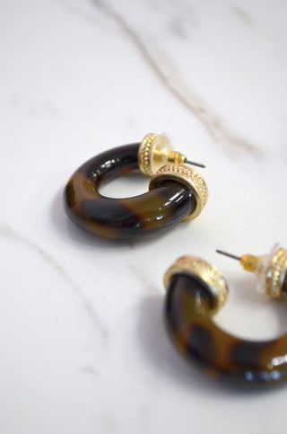 Pair of tortoiseshell hoop earrings with gold accents on a white background