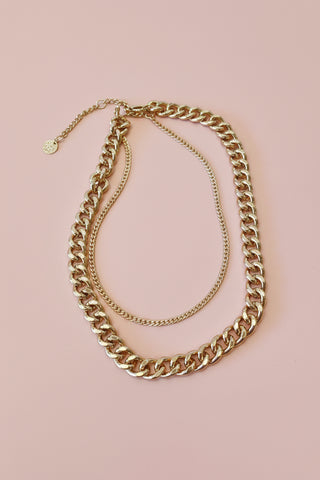 gold chain necklace on a blush tone surface