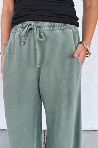 wide-leg, army green, terry sweatpants on a model in front of a building