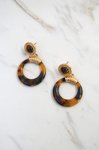 Tortoiseshell hoop earrings with gold accents on a white background