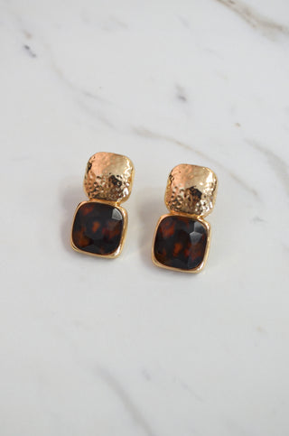 Gold and tortoiseshell square stud earrings on a marble background