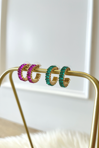 Pair of hoop earrings with colorful crystals  on a gold stand against a white background