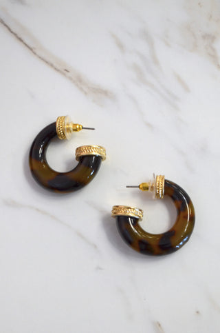 Tortoiseshell hoop earrings with gold accents on a marble surface