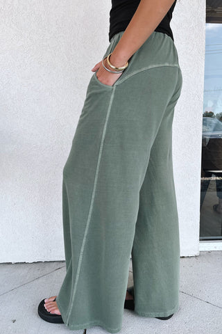 wide-leg, army green, terry sweatpants on a model in front of a building