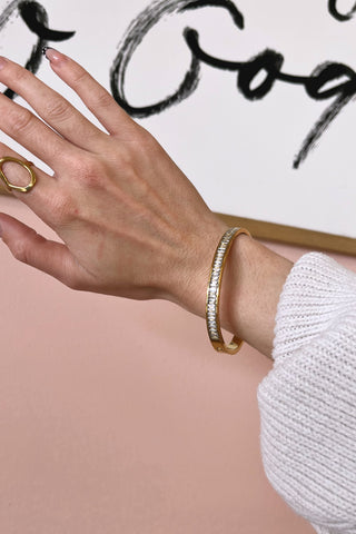 Hand wearing a gold bracelet with a blurred background
