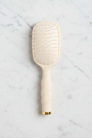 Beige paddle hairbrush with gold accents on a white background