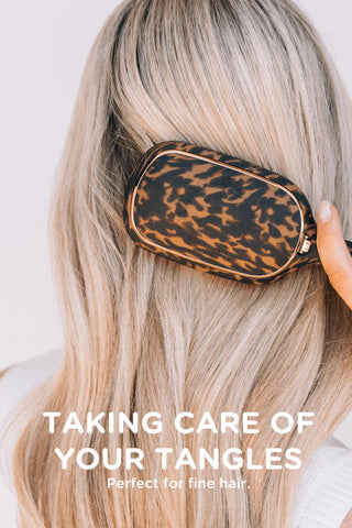 Person using a tortoise shell hairbrush on their blonde hair with text 'Taking care of your tangles' and 'Perfect for fine hair'.