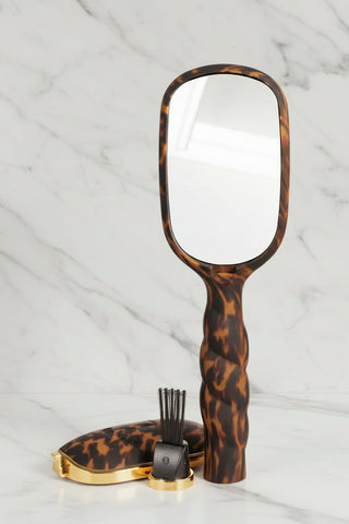 Handheld mirror with tortoiseshell handle on a white background