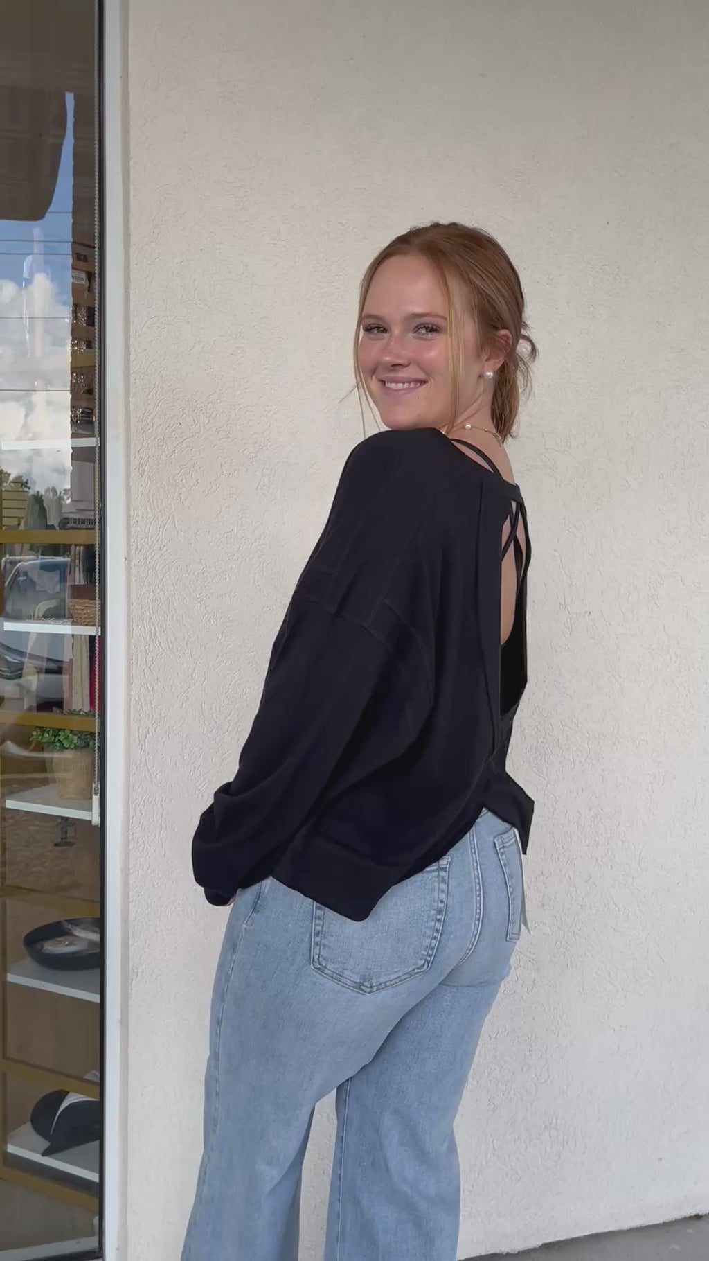 Model wearing an open-back black t-shirt that has long sleeves.