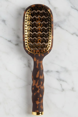 Hairbrush with tortoiseshell handle and wavy bristle pattern on a white background